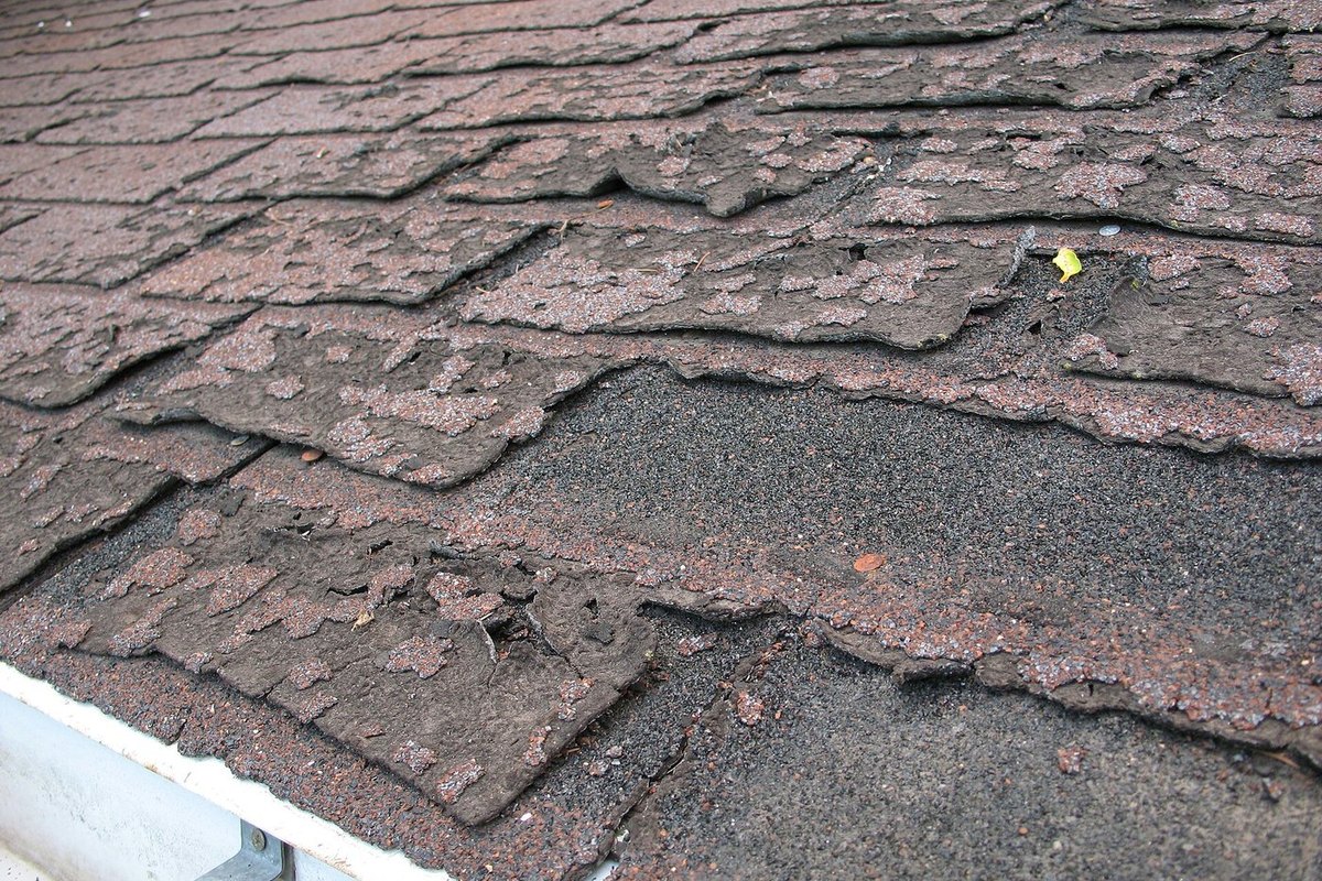 Lifted and failing asphalt shingles on an older roof