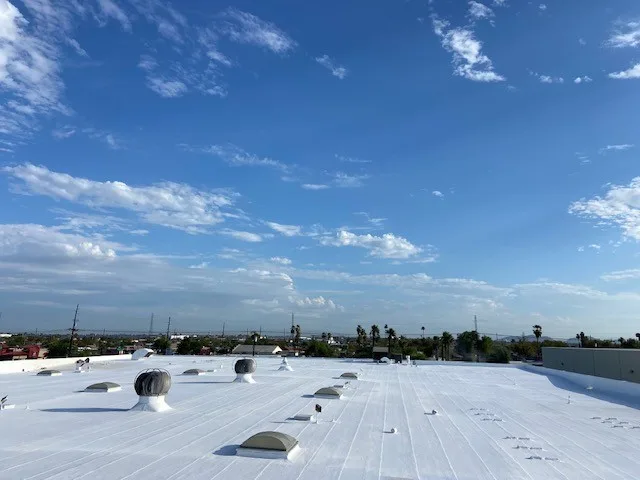 Finished white foam flat roof with fresh coating under a blue Arizona sky