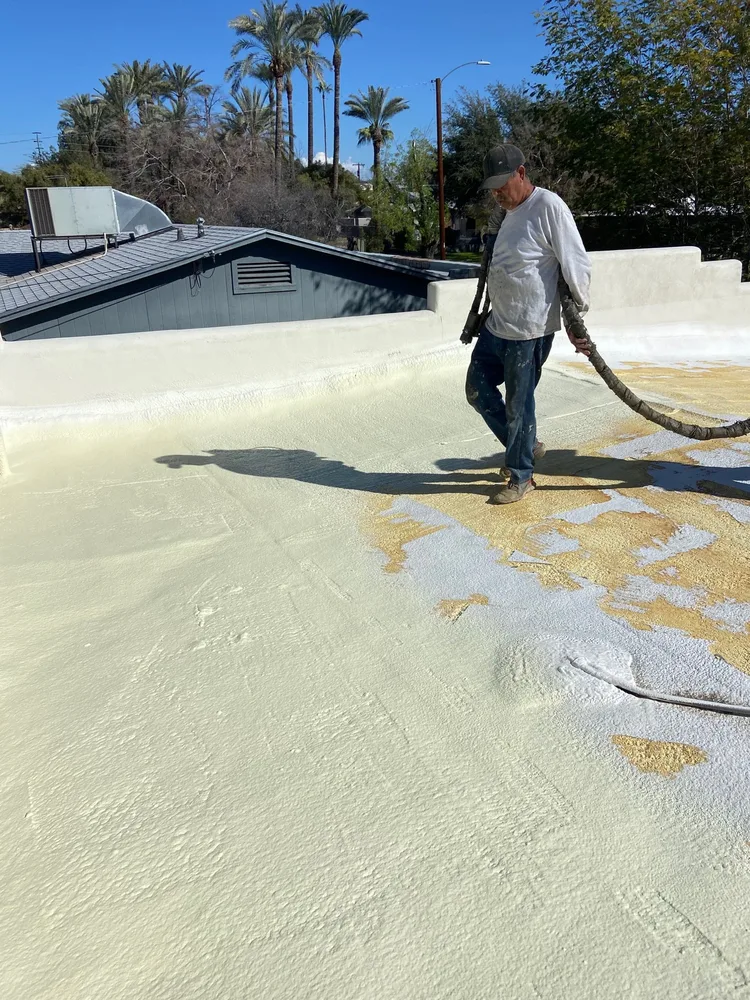 Circle G Roofing crew member spraying new foam on a flat roof in the Phoenix area