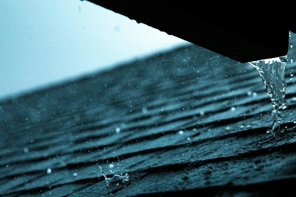 Water running off the edge of an asphalt shingle roof